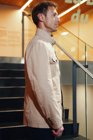 Homme de profil portant la saharienne  VANILLA beige. Elle comporte 2 poches poitrine et 2 poches à rabat.