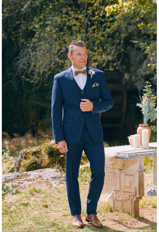 Homme de face en  Costume SUAT micro dessin couleur  marine 3 pièces devant une cascades.