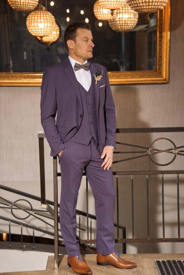 Homme de face en costume SUAT violet 3 pièces une cours. Il porte des chaussures marrons.