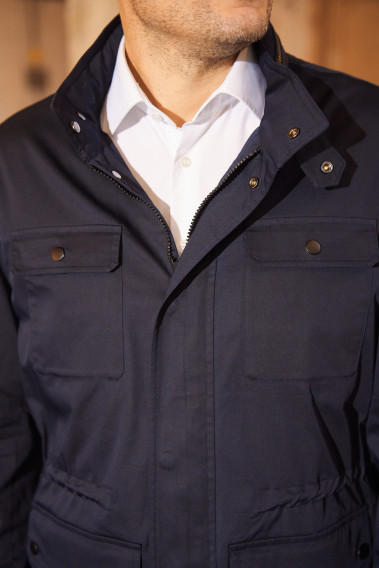 Zoom sur la surveste AUBURNE marine. Elle possède un col droit et une fermeture éclair et des boutons pressions cachés.