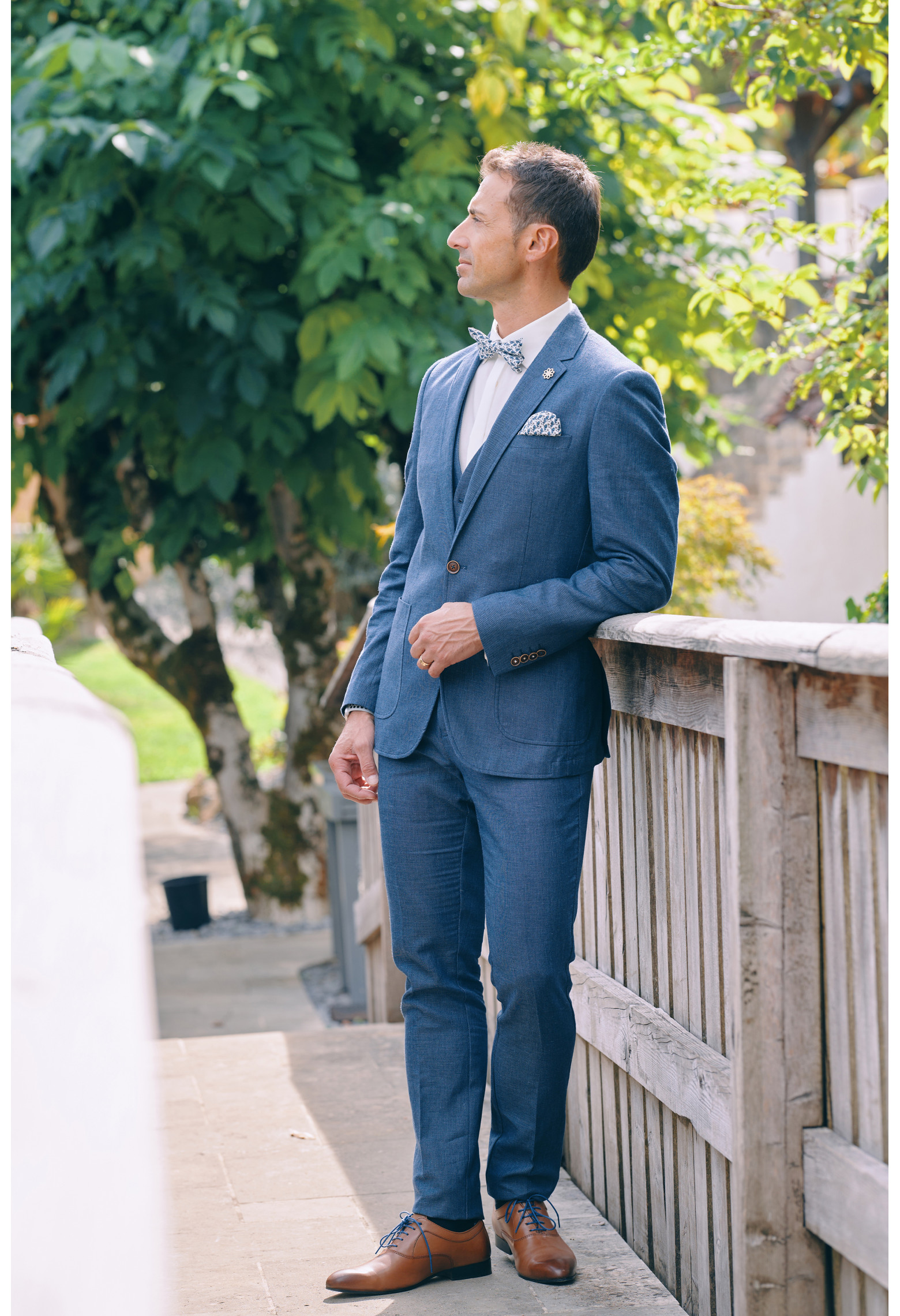 Homme en position trois-quarts en costume GIORGIO couleur bleu sur un pont.