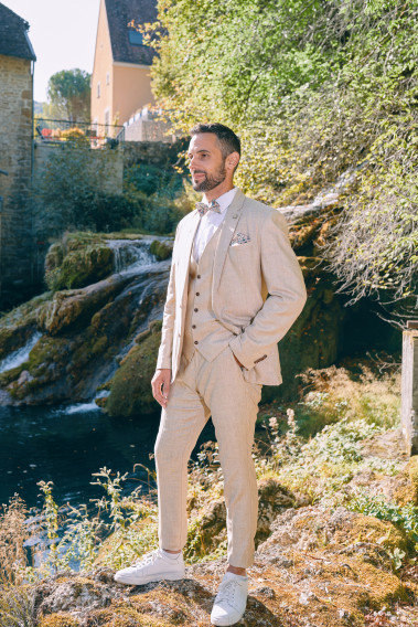 Homme en position trois-quarts en costume GIORGIO couleur sable 3 pièces sur un rocher.