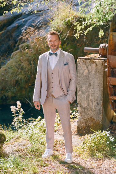 Homme de profil portant la veste TROPICAL rose poudré. Elle comporte une poche poitrine et 2 poches plaquées.