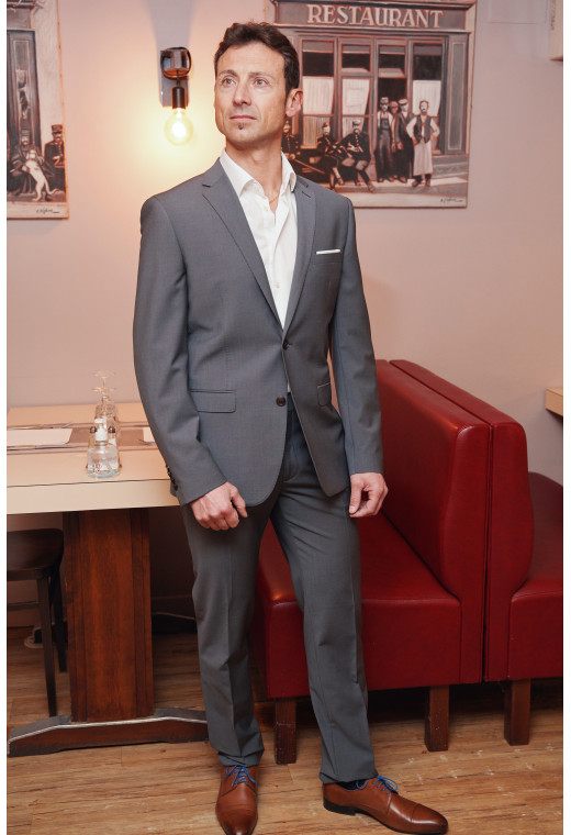 Homme portant la veste TECHV grise. Elle comporte une poche poitrine et 2 poches à rabat.