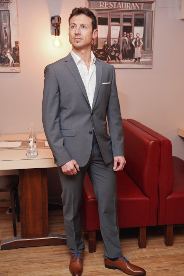 Homme portant la veste TECHV grise. Elle comporte une poche poitrine et 2 poches à rabat.