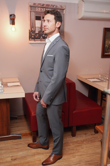 Homme portant la veste TECHV grise. Elle comporte une poche poitrine et 2 poches à rabat.