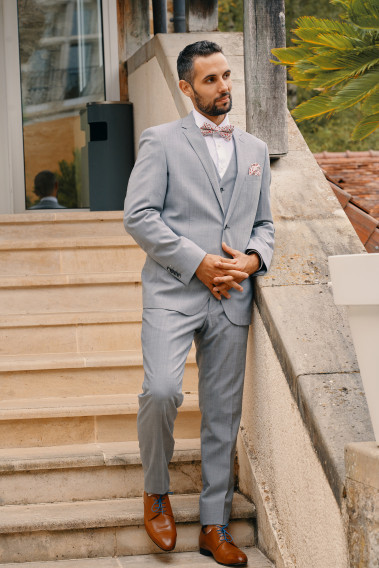 Homme portant la veste TECHV gris clair. Elle comporte une poche poitrine et 2 poches à rabat.