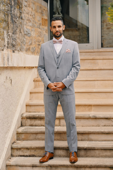 Homme portant la veste TECHV gris clair. Elle comporte une poche poitrine et 2 poches à rabat.