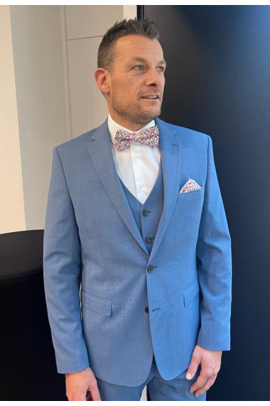 Homme de face en costume SUAT couleur bleu 3 pièces dans une salle.