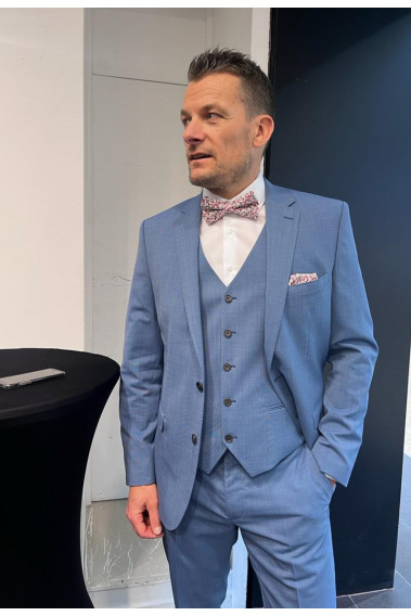 Homme de face en costume SUAT couleur bleu 3 pièces dans une salle.