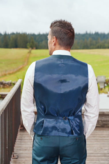 Homme de dos portant le gilet CHRIS bleu vert. Il comporte une patte de serrage dans le dos.