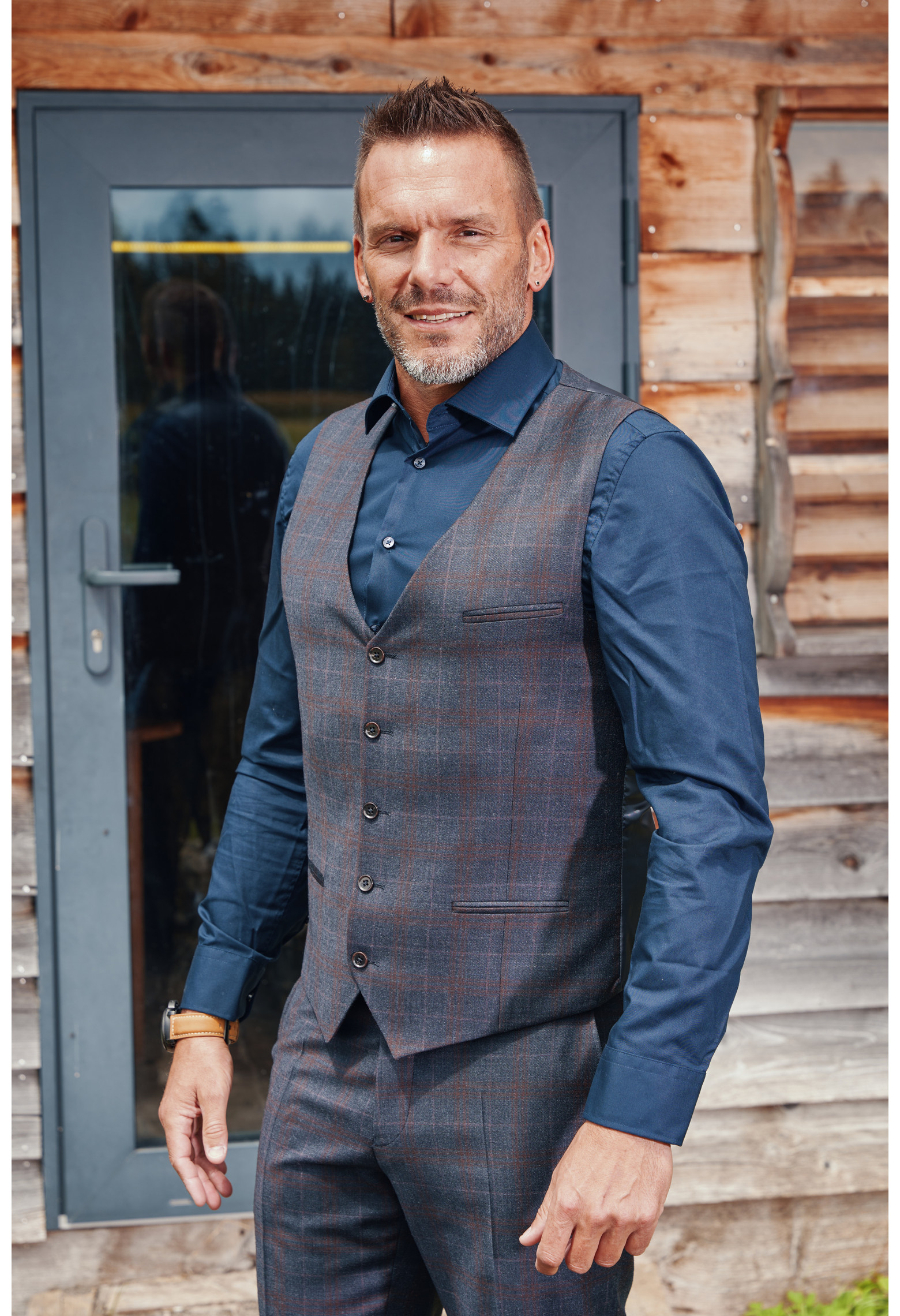 Homme de face portant le gilet CHRIS carreaux bordeaux. Elle comporte 5 boutons.