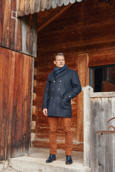 Homme portant le manteau caban LUCERNE marine. Il est long et comporte 2 poches poitrines et 2 poches plaquées.