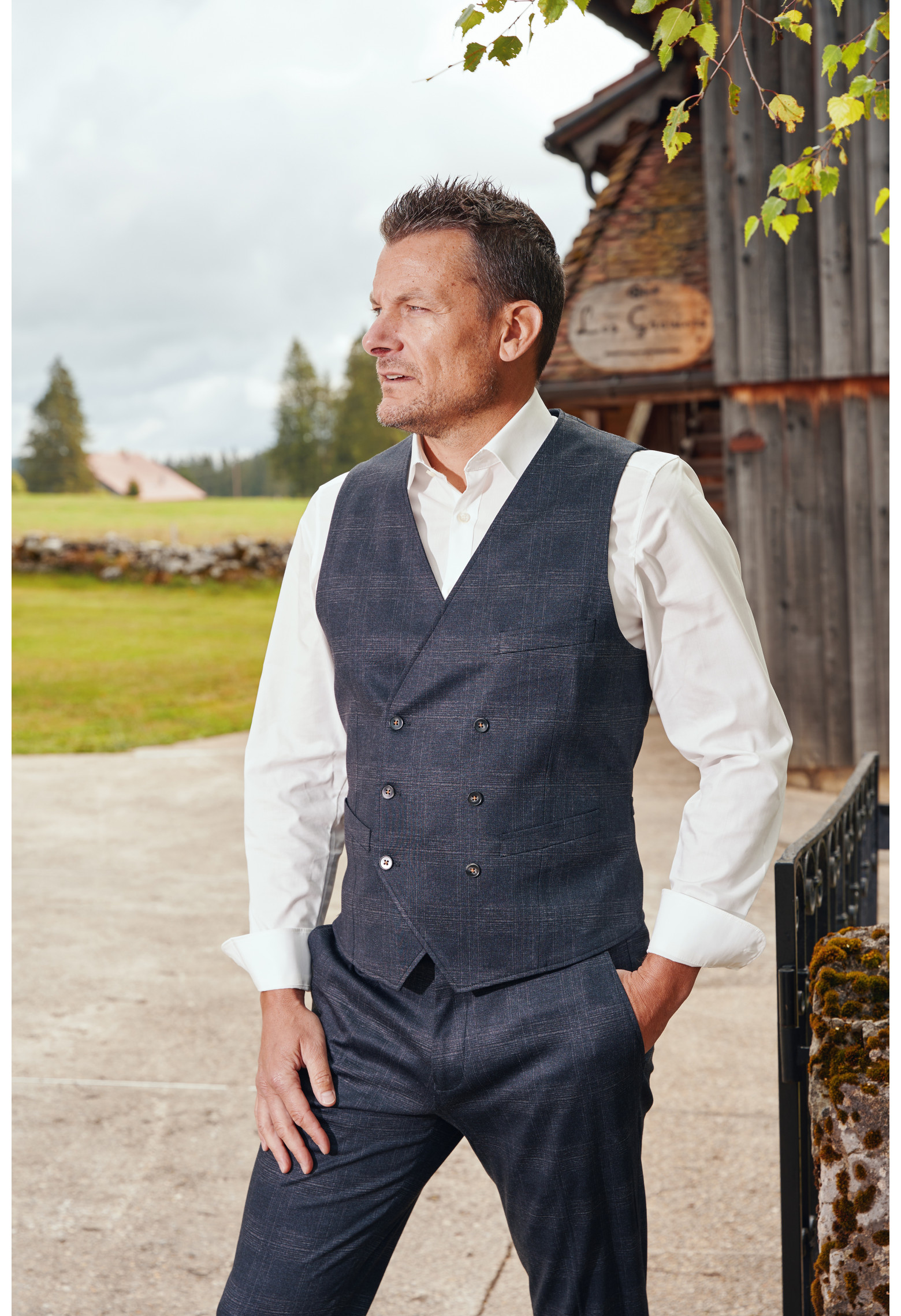 Homme de face portant le gilet PIANOSA  carreaux gris. Elle comporte 6 boutons.