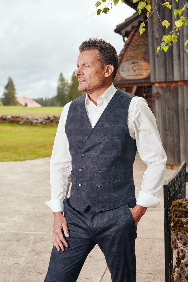 Homme de face portant le gilet PIANOSA  carreaux gris. Elle comporte 6 boutons.