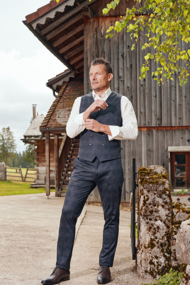 Homme de face portant le gilet PIANOSA  carreaux gris. Elle comporte 6 boutons.