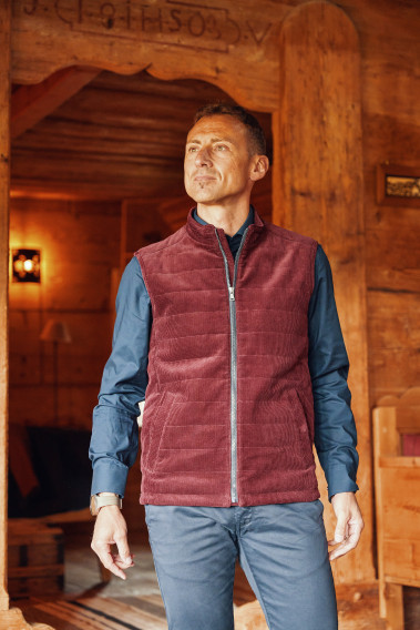 Homme portant la doudoune sans manches PILAT bordeaux. Elle comporte 2 poches repose mains.