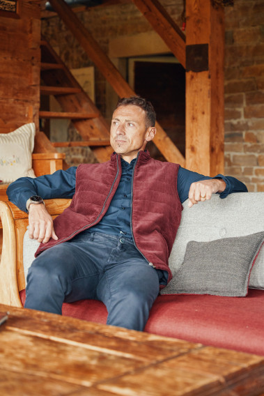 Homme portant la doudoune sans manches PILAT bordeaux. Elle comporte 2 poches repose mains.