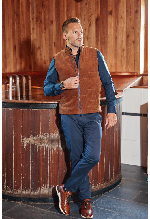 Homme portant la doudoune sans manches PILAT camel. Elle comporte 2 poches repose mains.