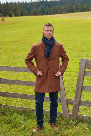 Homme portant le manteau SUAVE camel. Il est long et comporte 3 poches intérieures dont une pour le téléphone.