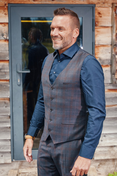 Homme en position trois-quarts  portant le gilet CHRIS carreaux bordeaux. Elle comporte 5 boutons.