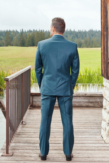 Homme de dos en costume CITIZEN bleu vert 2 pièces. Il porte des chaussures marrons.