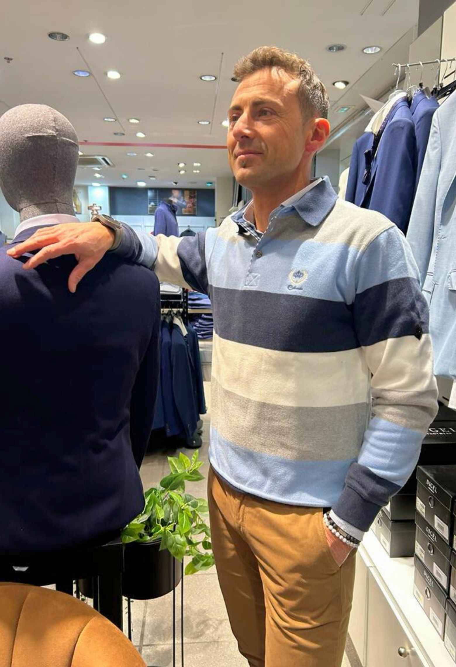 Homme portant le polo manches longues bleu à rayures. Col chemise et coupe droite.