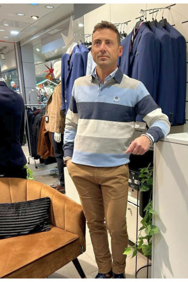 Homme portant le polo manches longues bleu à rayures. Col chemise et coupe droite.