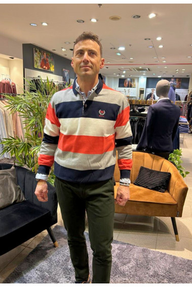 Homme portant le polo manches longues orange à rayures. Col chemise et coupe classique.