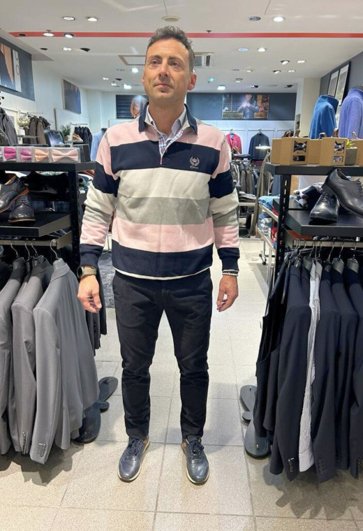 Homme portant le polo manches longues roses à rayures. col chemise et coupe classique.