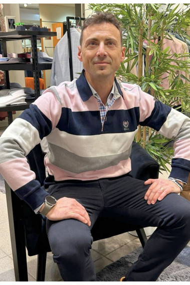 Homme portant le polo manches longues roses à rayures. col chemise et coupe classique.