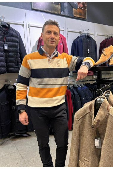 Homme portant le polo manches longues ocre à rayures. Coupe classique.