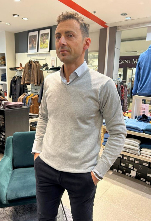 Homme portant le pull col V gris clair avec une chemise. Coupe regular.