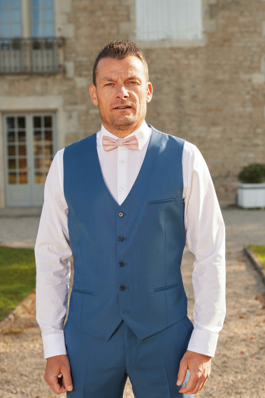 Homme portant le gilet CHRIS bleu accompagné d'un nœuds papillon.