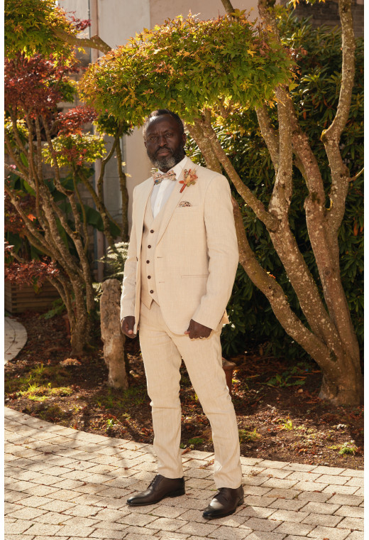 Homme en position trois-quarts en costume GIORGIOC couleur beige 3 pièces dans une cours.