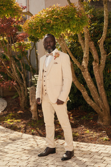 Homme en position trois-quarts en costume GIORGIOC couleur beige 3 pièces dans une cours.