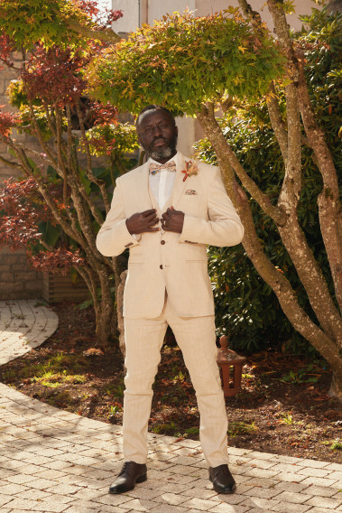 Homme de face en costume GIORGIOC couleur beige 3 pièces dans une cours.