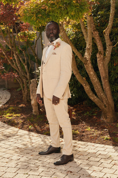 Homme en position trois-quarts en costume GIORGIOC couleur beige 3 pièces dans une cours.