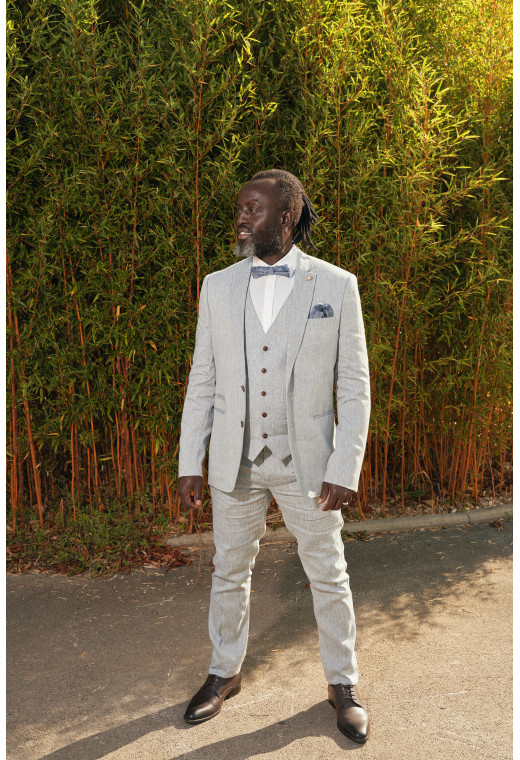 Homme de face en costume GIORGIO couleur bleu clair 3 pièces dans une cours. Il porte des chaussures marrons.
