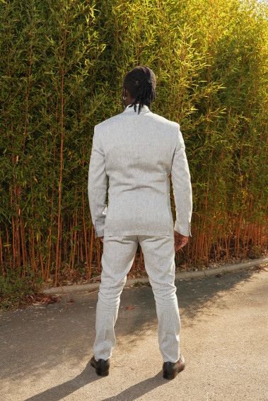 Homme de dos en costume GIORGIO couleur bleu clair 3 pièces dans une cours. Il porte des chaussures marrons.