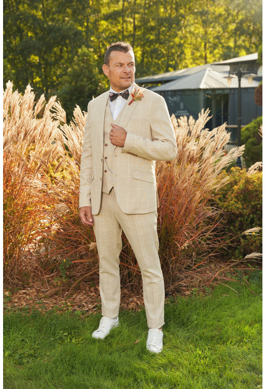 Homme de face en costume GIORGIOC couleur beige à carreaux 3 pièces dans une cours.