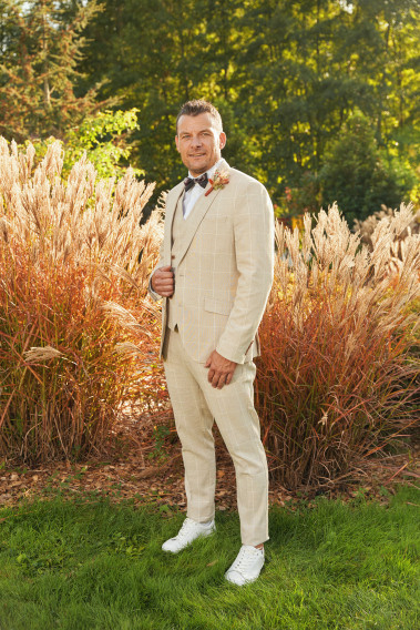 Homme de face en costume GIORGIOC couleur beige à carreaux 3 pièces dans une cours.