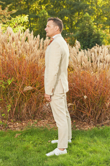 Homme de profil en costume GIORGIOC couleur beige à carreaux dans une cours.