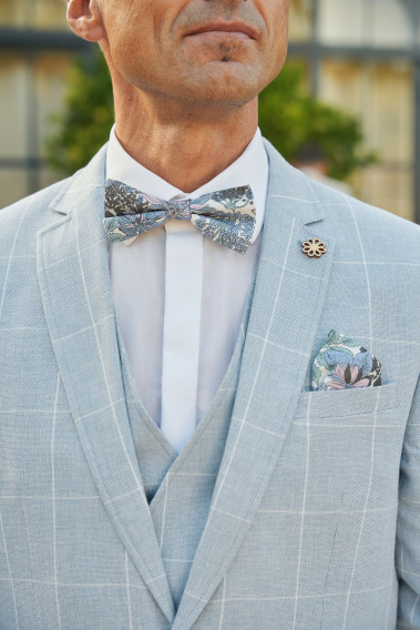 Costume GIORGIOC bleu à carreaux. Plan sur le nœuds  papillon à motif florale avec son mouchoir de poche.