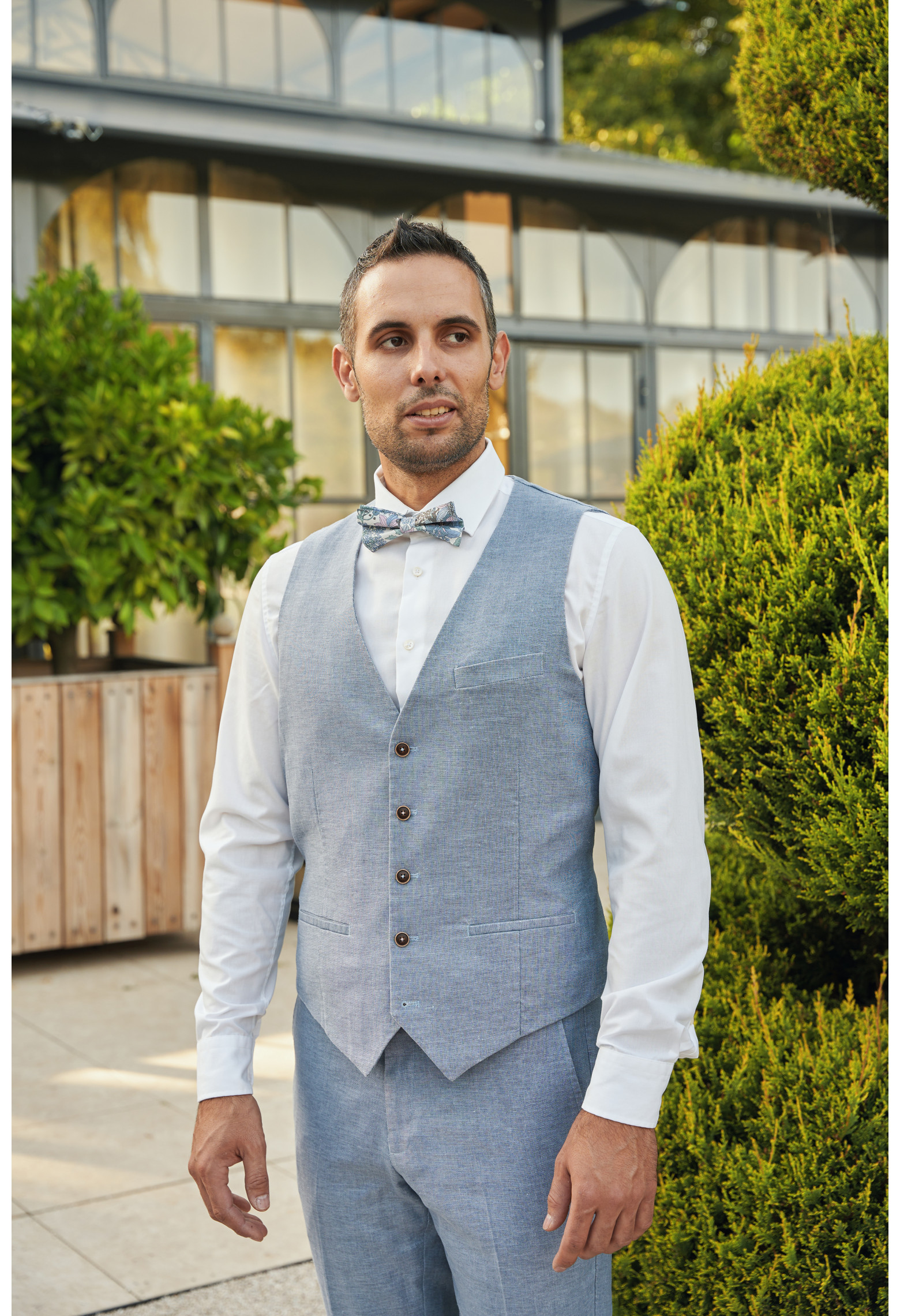 Homme portant le gilet LYMAW bleu accompagné d'un nœuds papillon.