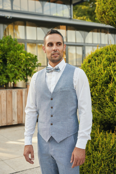 Homme portant le gilet LYMAW bleu accompagné d'un nœuds papillon.