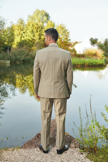 Homme de dos en costume SUAT tilleul 3 pièces vers un lac.