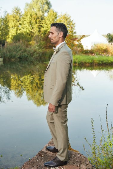 Homme de profil en costume SUAT tilleul 3 pièces vers un lac. Il porte des chaussures marrons.