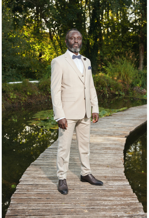 Homme en position trois-quarts en costume SUAT de couleur craie 3 pièces sur un pont dans un lac.