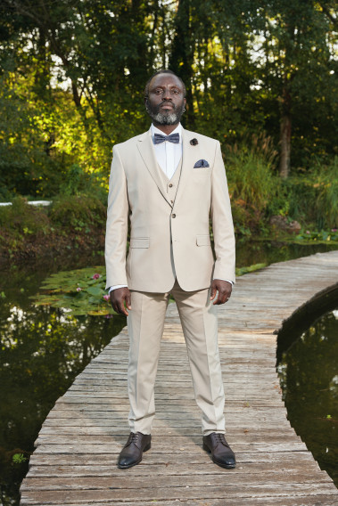Homme de face en costume SUAT de couleur craie 3 pièces sur un pont dans un lac.